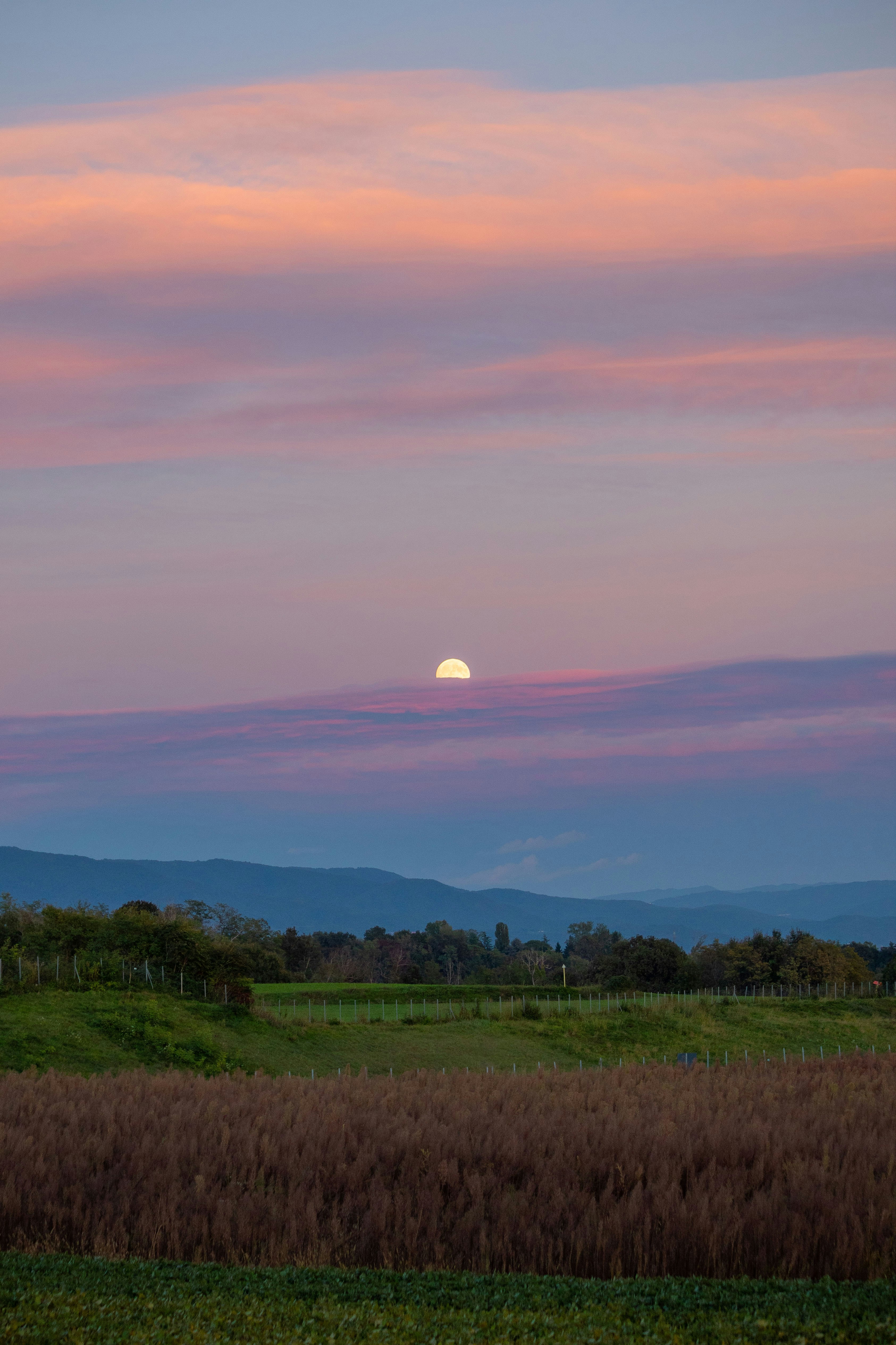 Full moon rising over a colorful sunset sky.