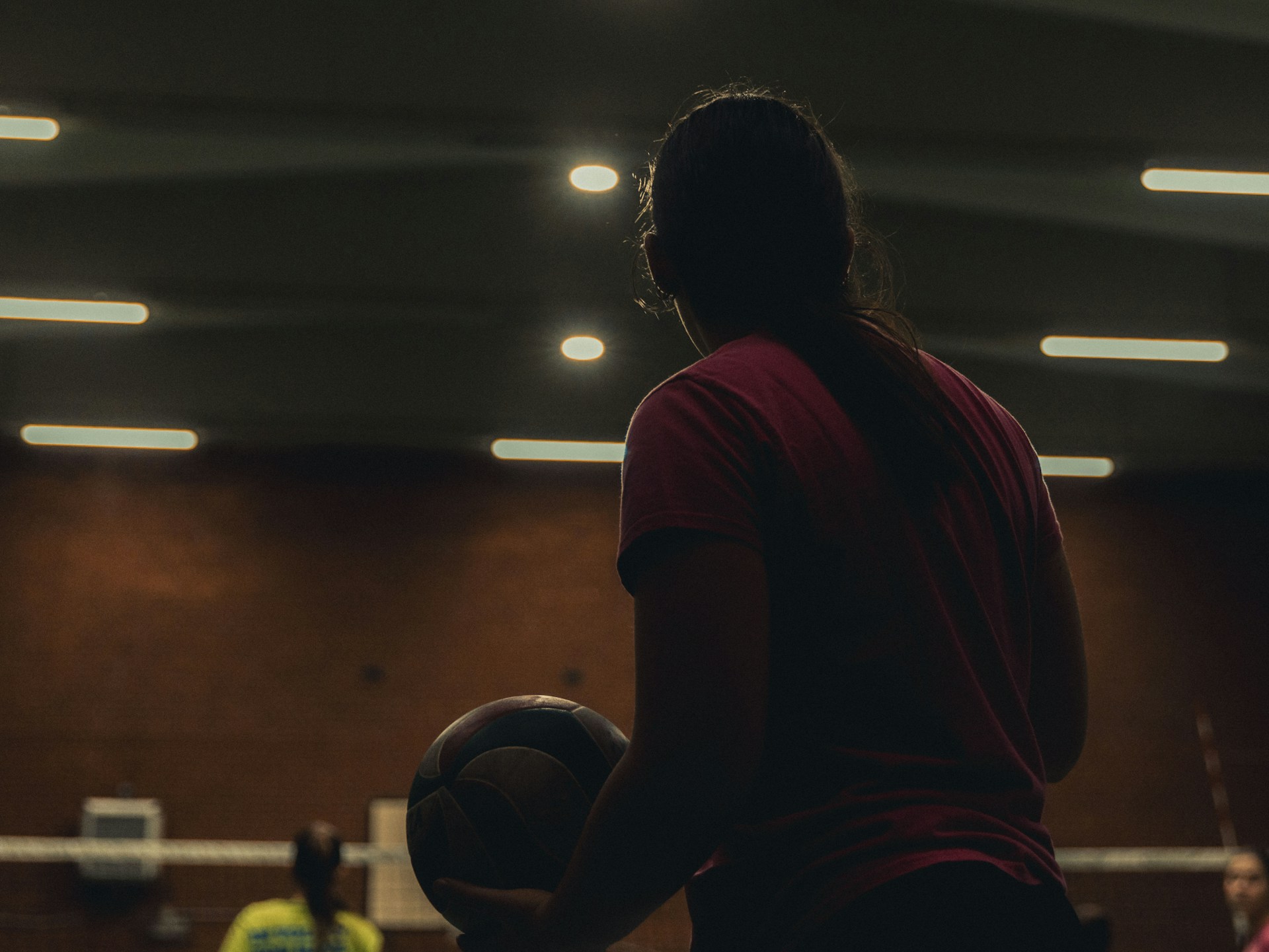 Young woman holding basketball in gymnasium.