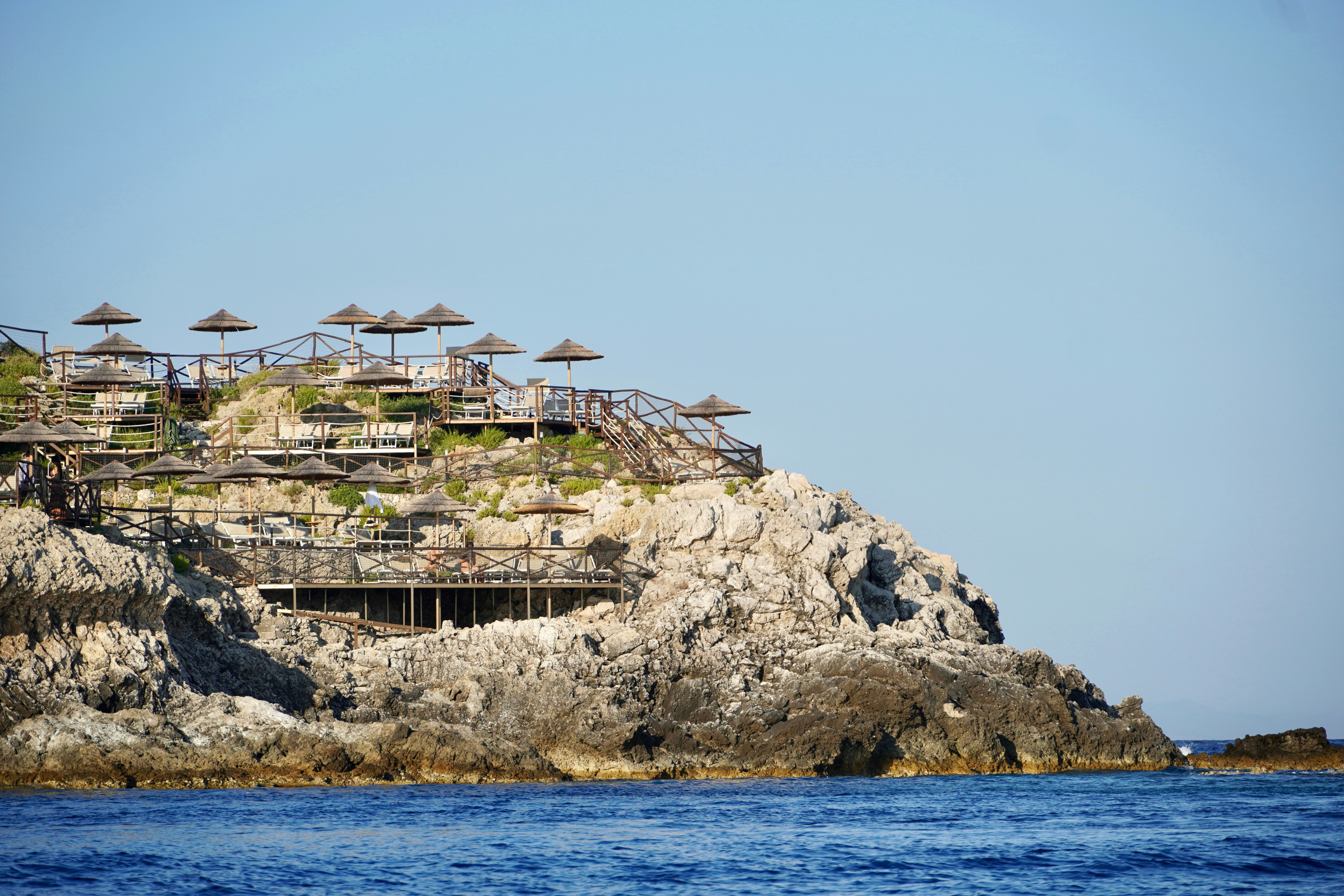 Rocky coastline with thatched umbrellas and wooden decks.