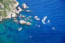 Boats navigate clear blue water near rocky coastline.