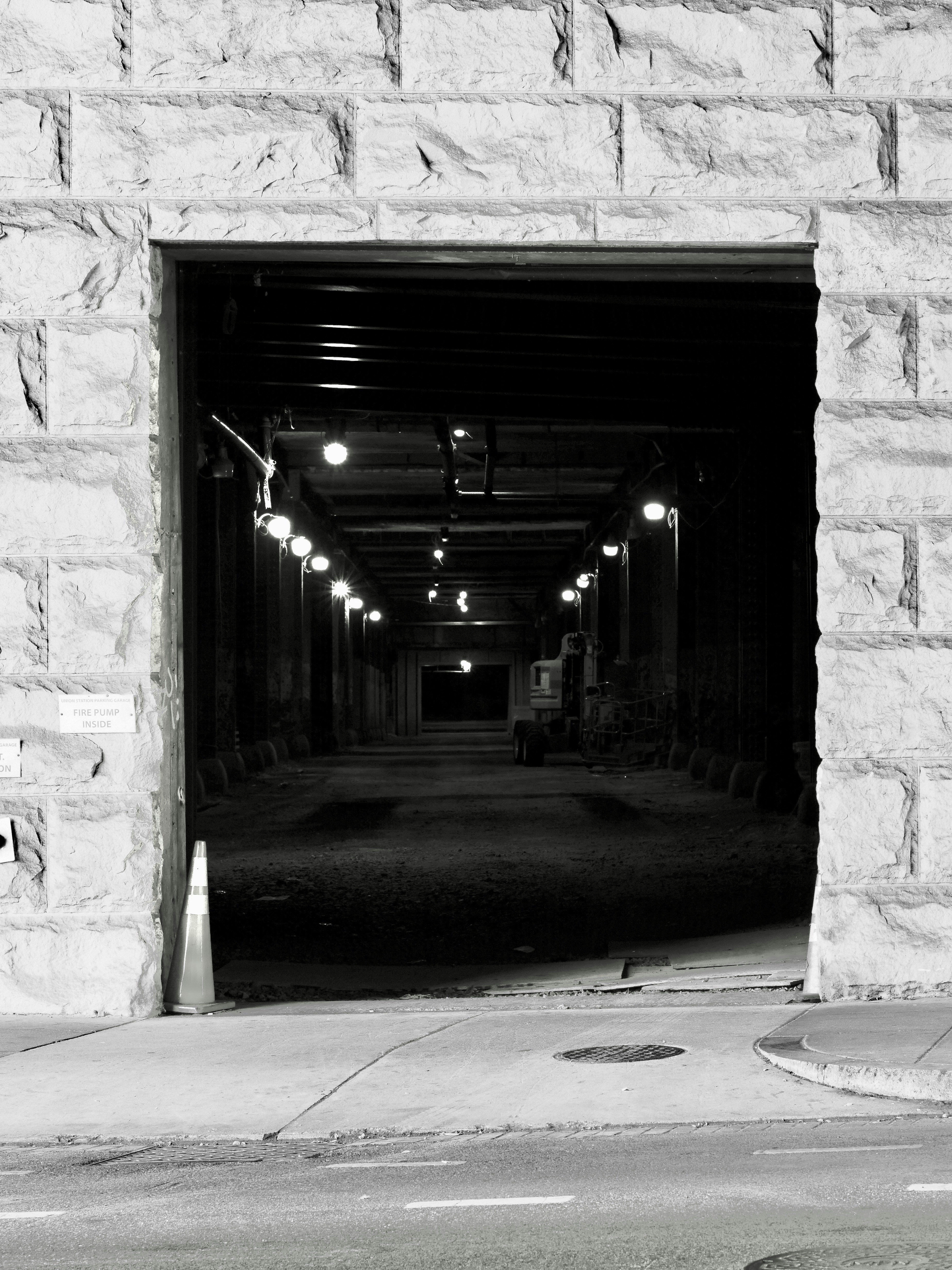 Entrance to a dark, stone tunnel with lights.