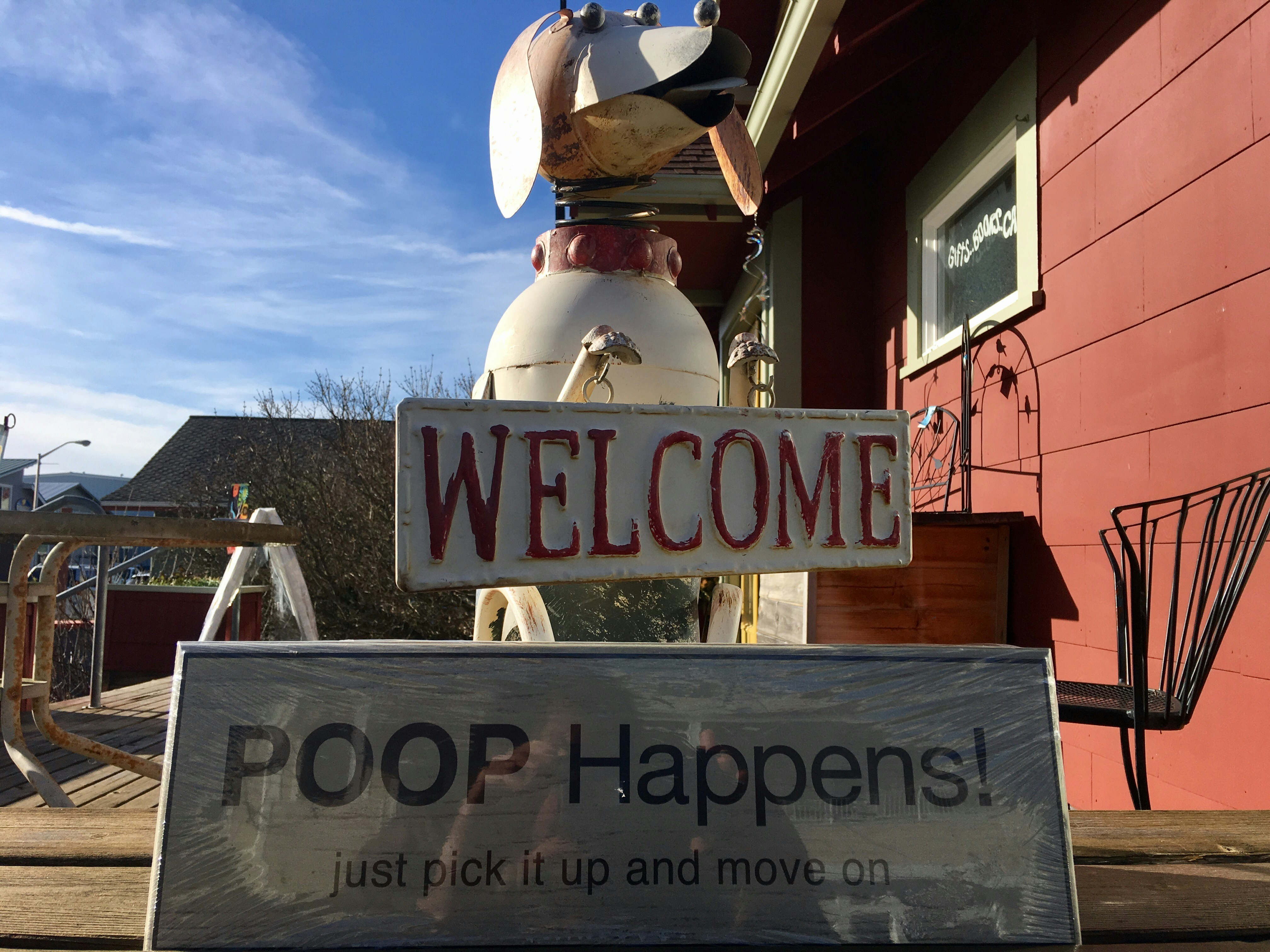 Dog sculpture with welcome and poop happens signs