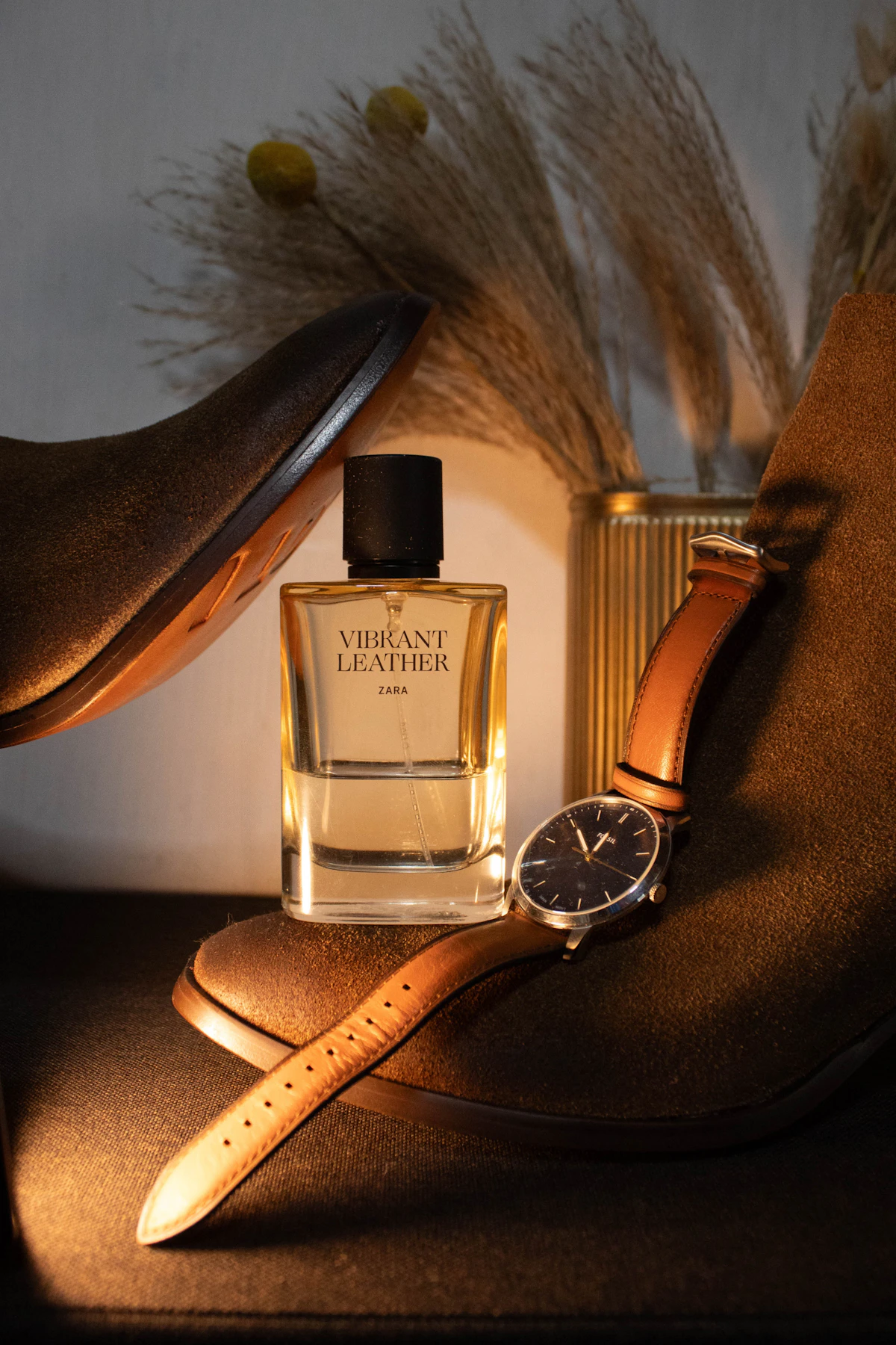 Frasco de perfume masculino ao lado de relógio e botas sobre a mesa
