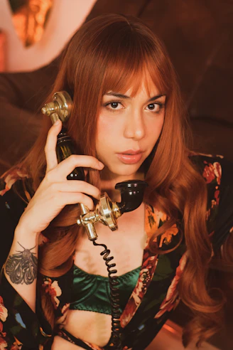 Woman with red hair holding an old telephone