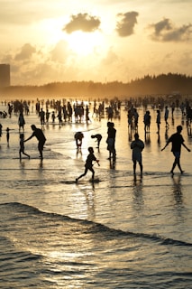 People enjoying a beach at sunset with gentle waves.