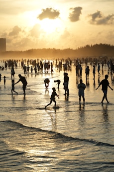 People enjoying a beach at sunset with gentle waves.