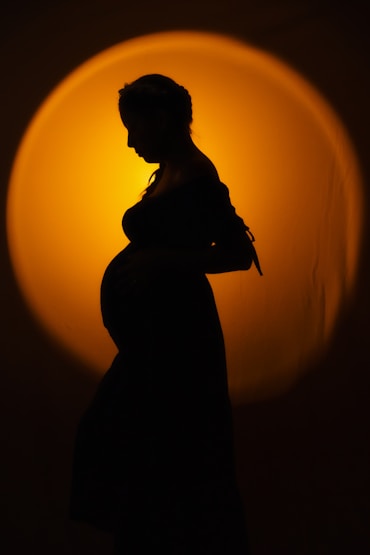 Silhouette of a pregnant woman against a warm light