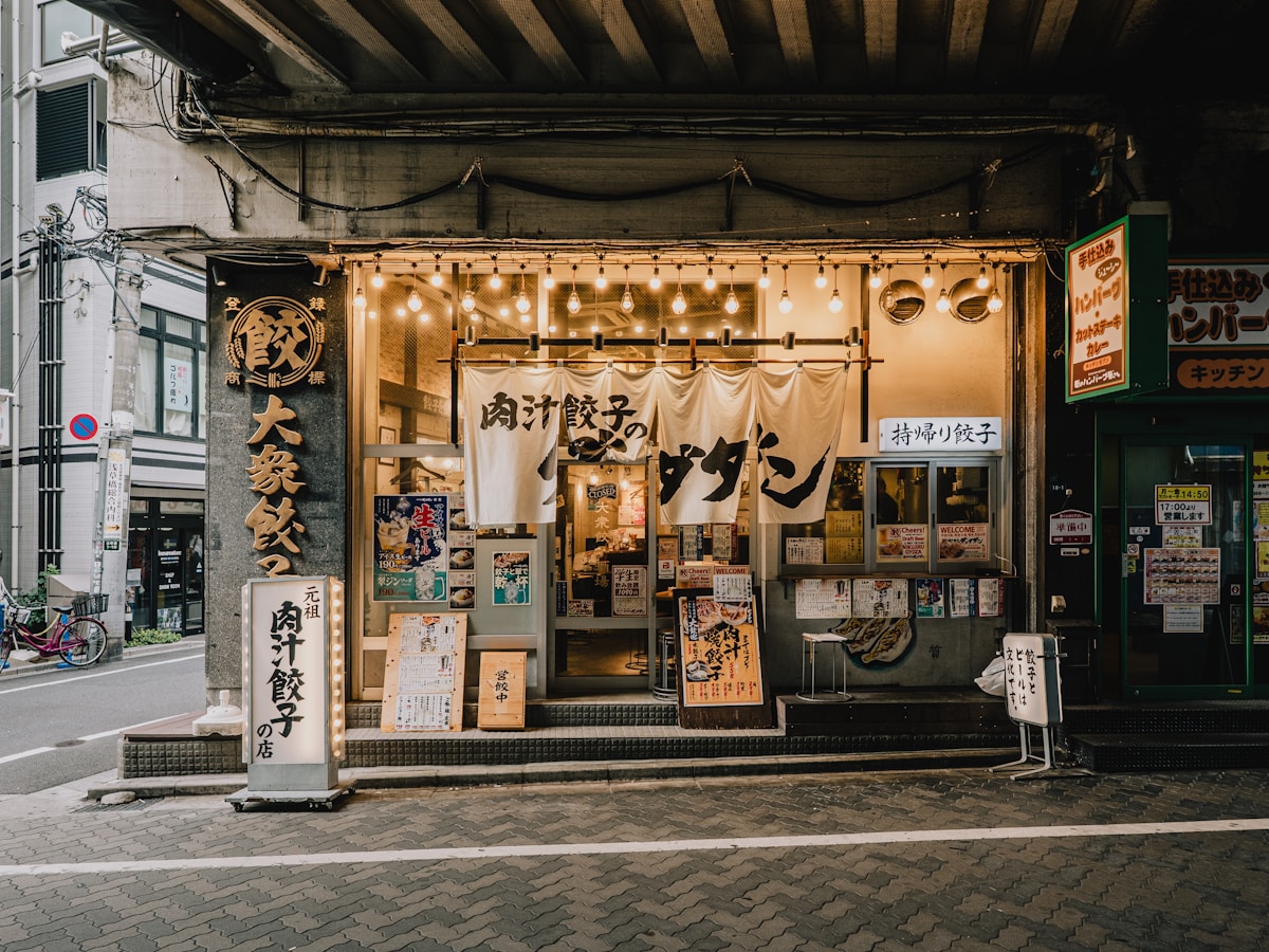A restaurant storefront lit up at dusk. Photo by Vinicius Brasil on Unsplash.