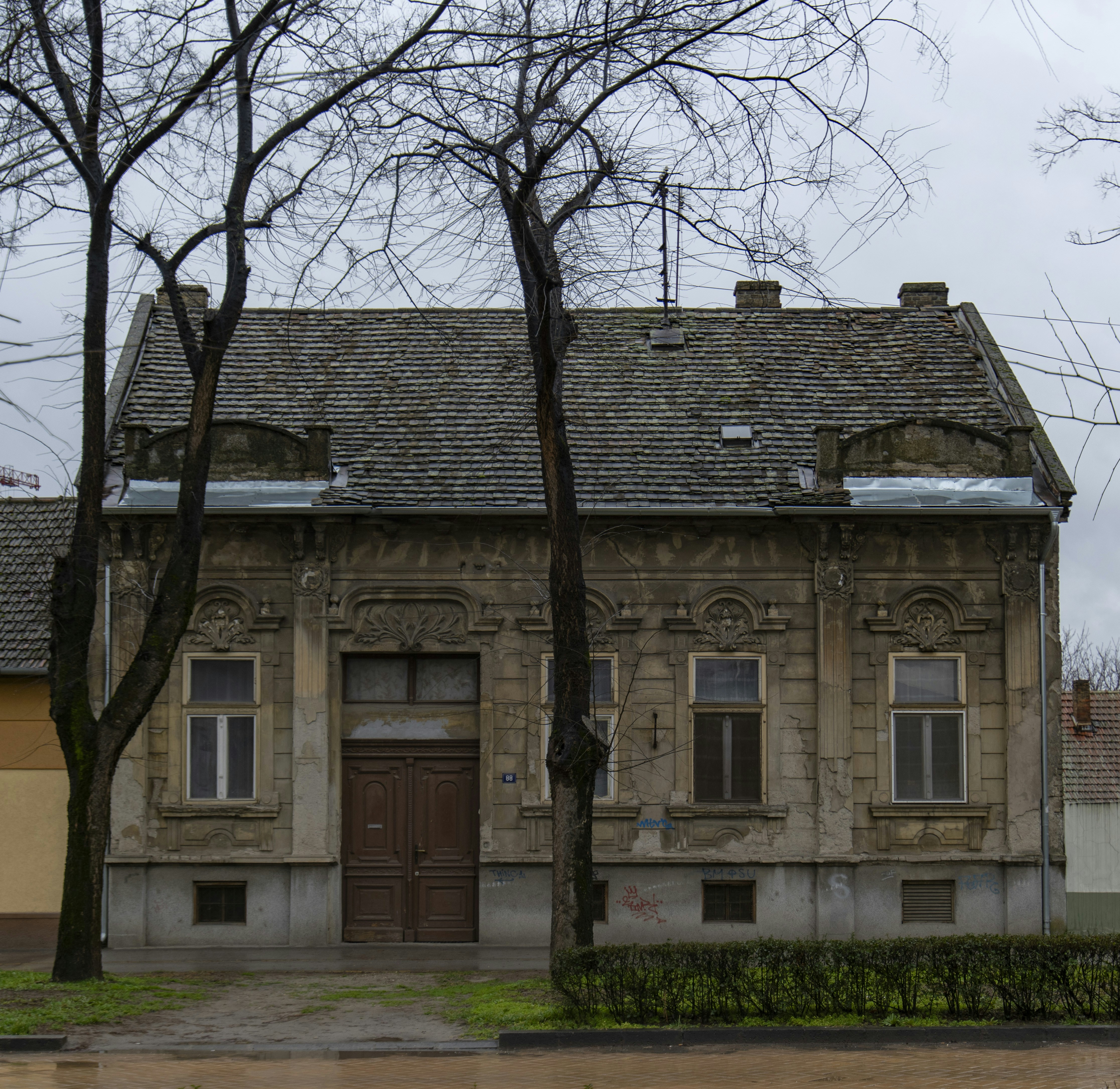 Older distressed house with worn exterior and damaged roof, representing properties sold as-is for cash offers.
