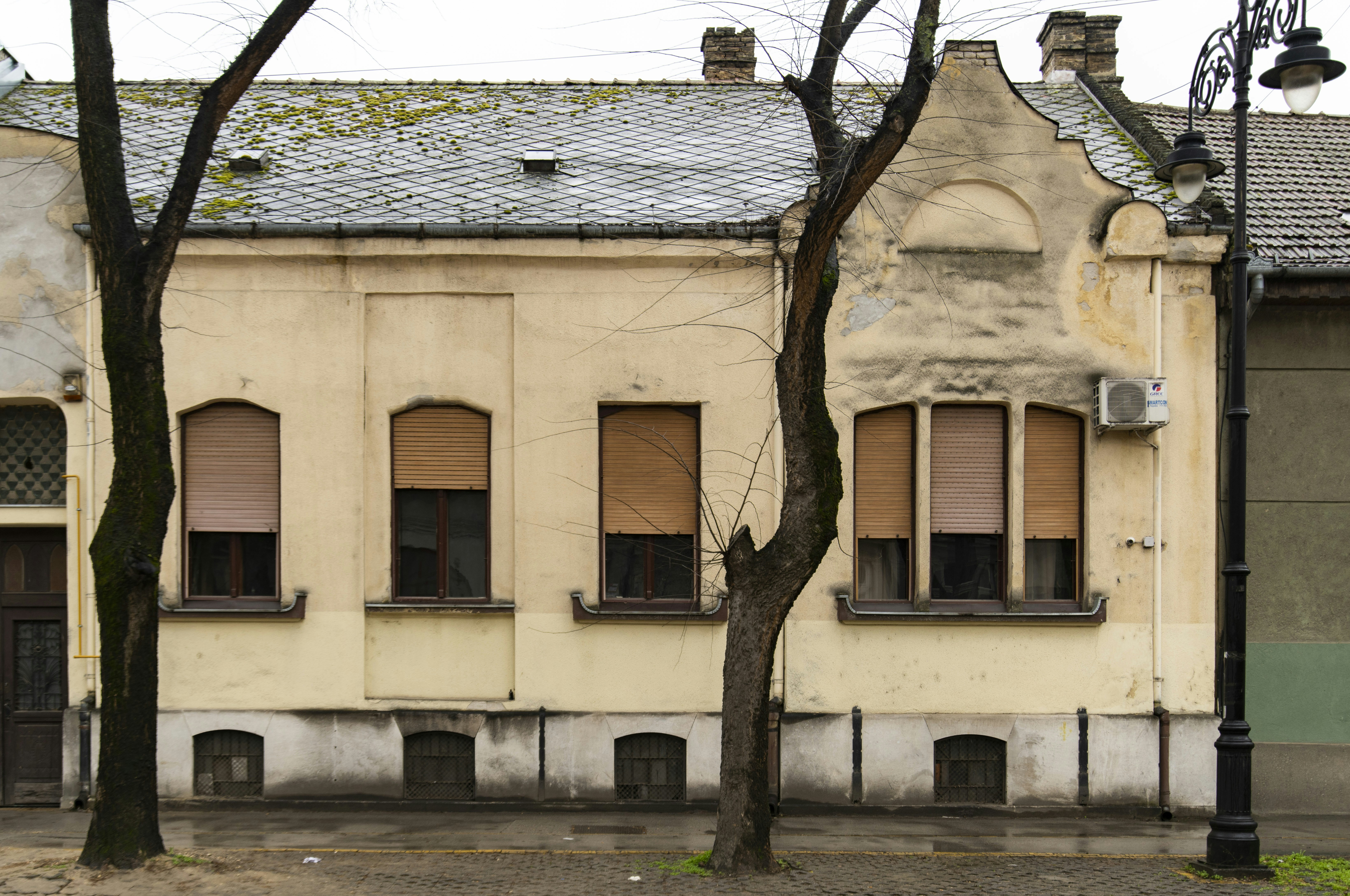 Old yellow building with trees and windows.