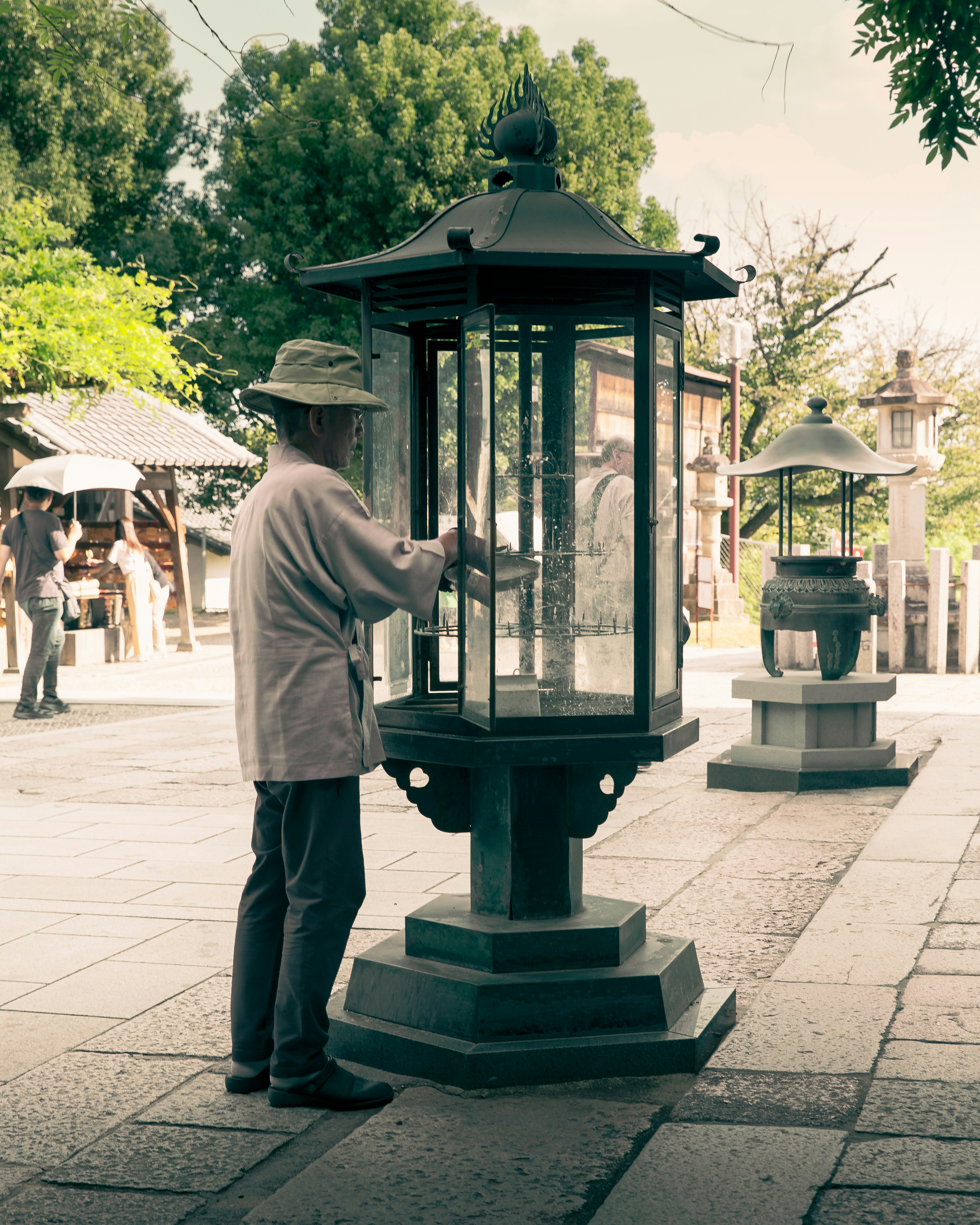 Man tending to a large lantern at a temple.
