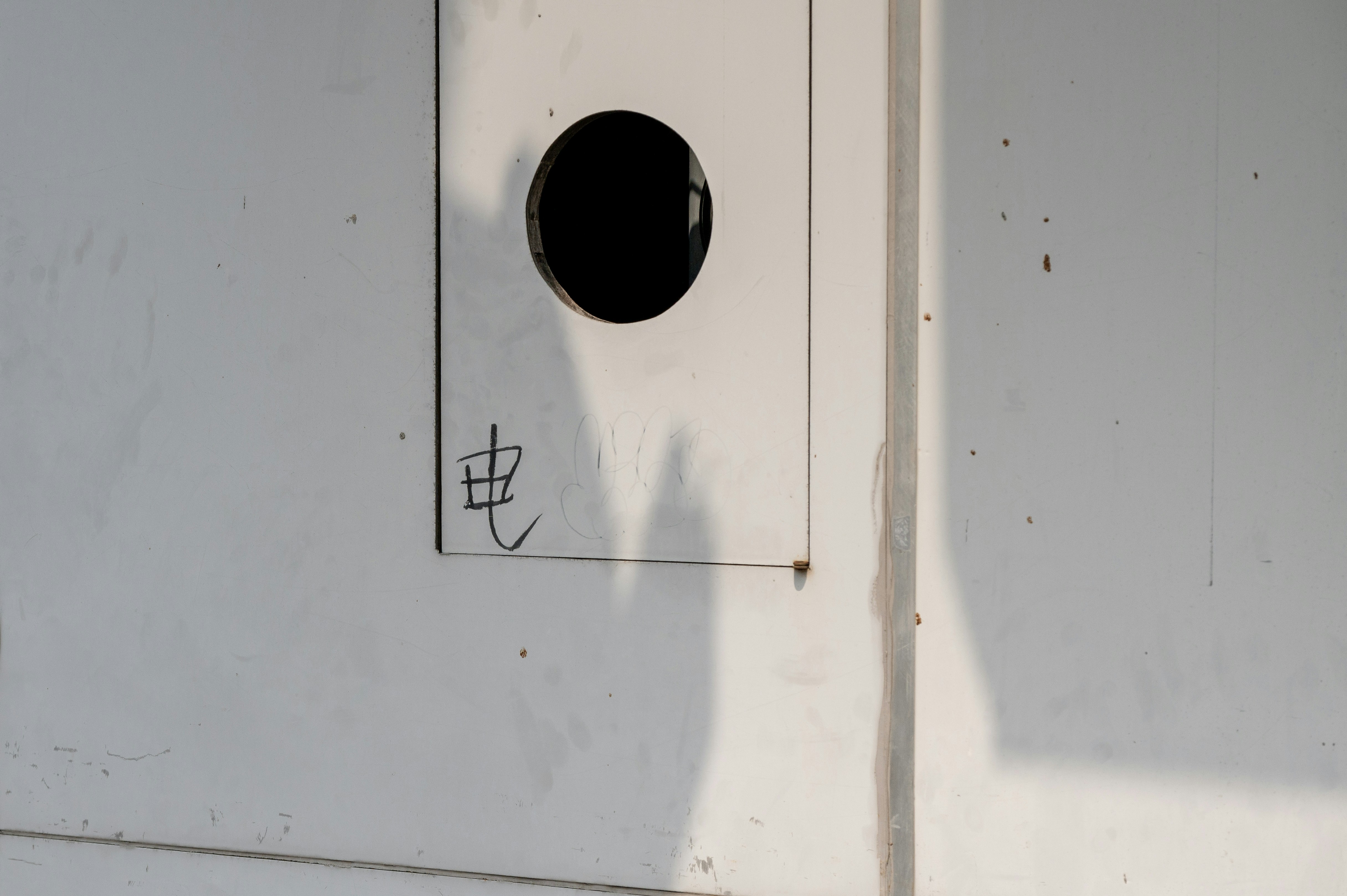 White wall with a black circle and japanese writing.