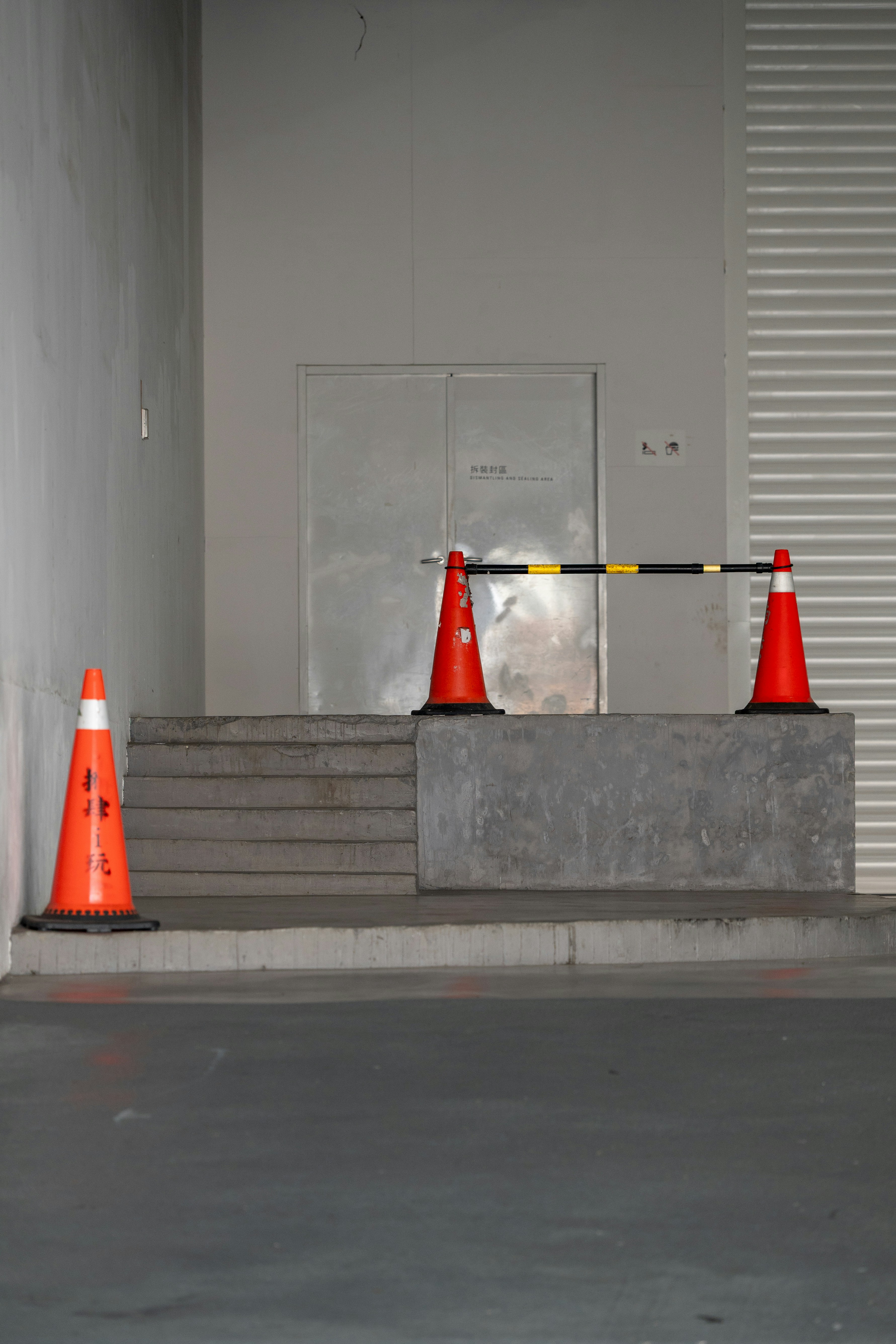 Orange traffic cones block a doorway on steps.