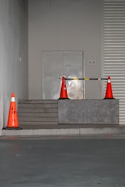 Orange traffic cones block a doorway on steps.