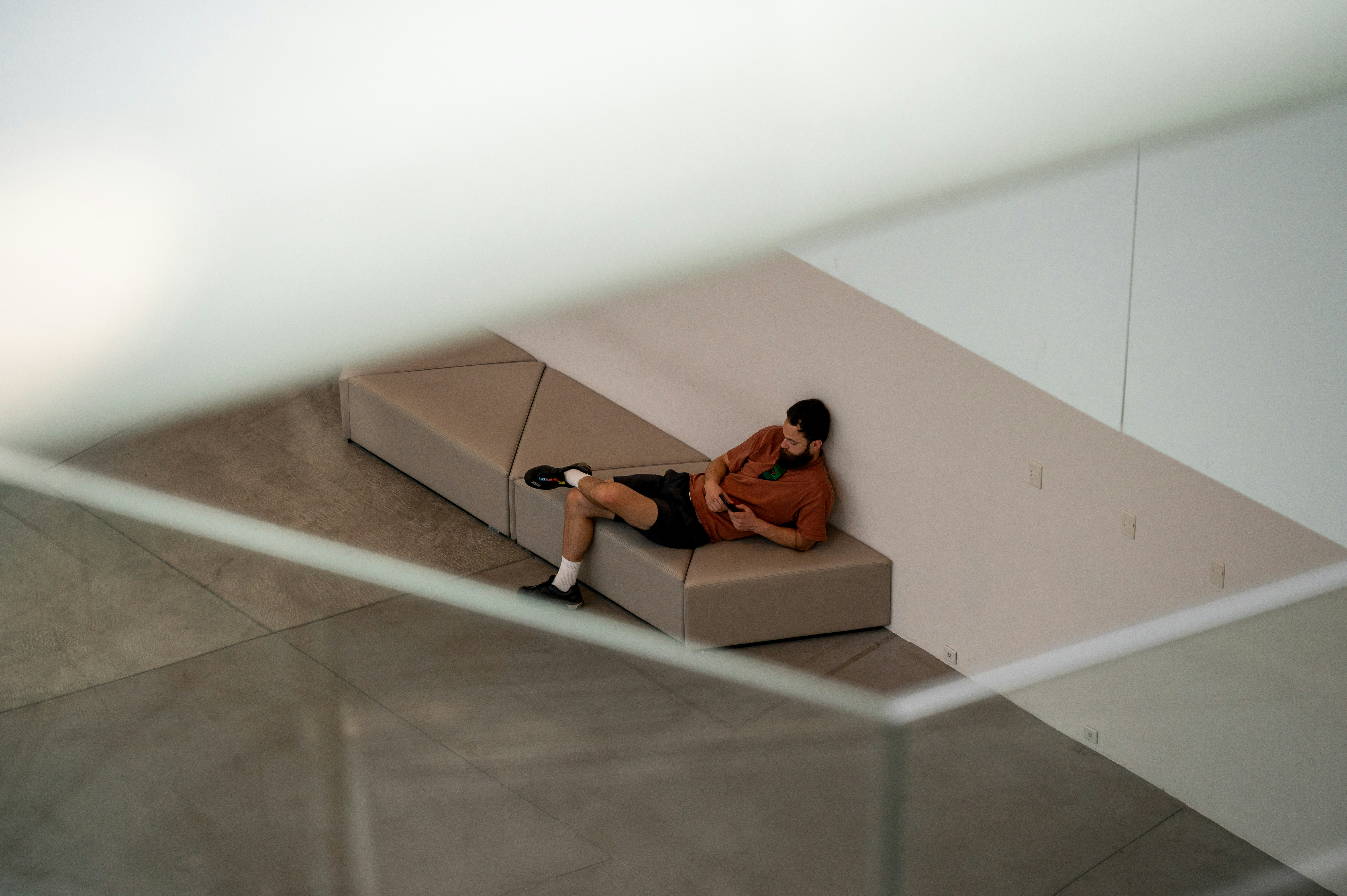 Man resting on a modern bench in a minimalist interior.
