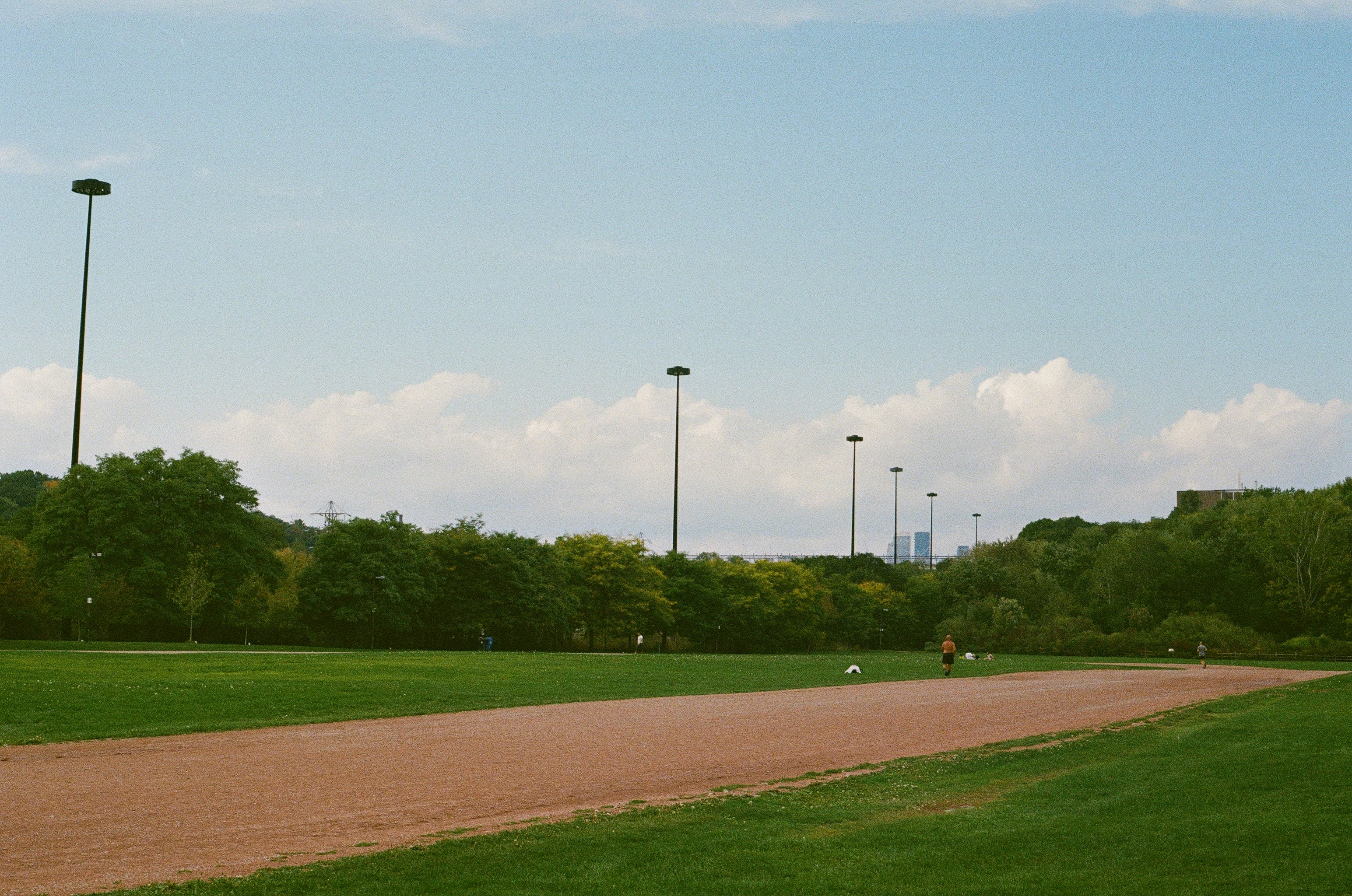 Green field with a running track and distant trees.