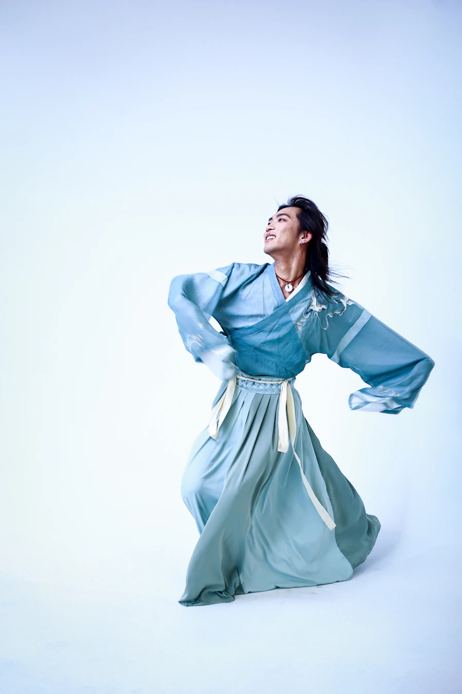 A practitioner in flowing blue silk moving gracefully