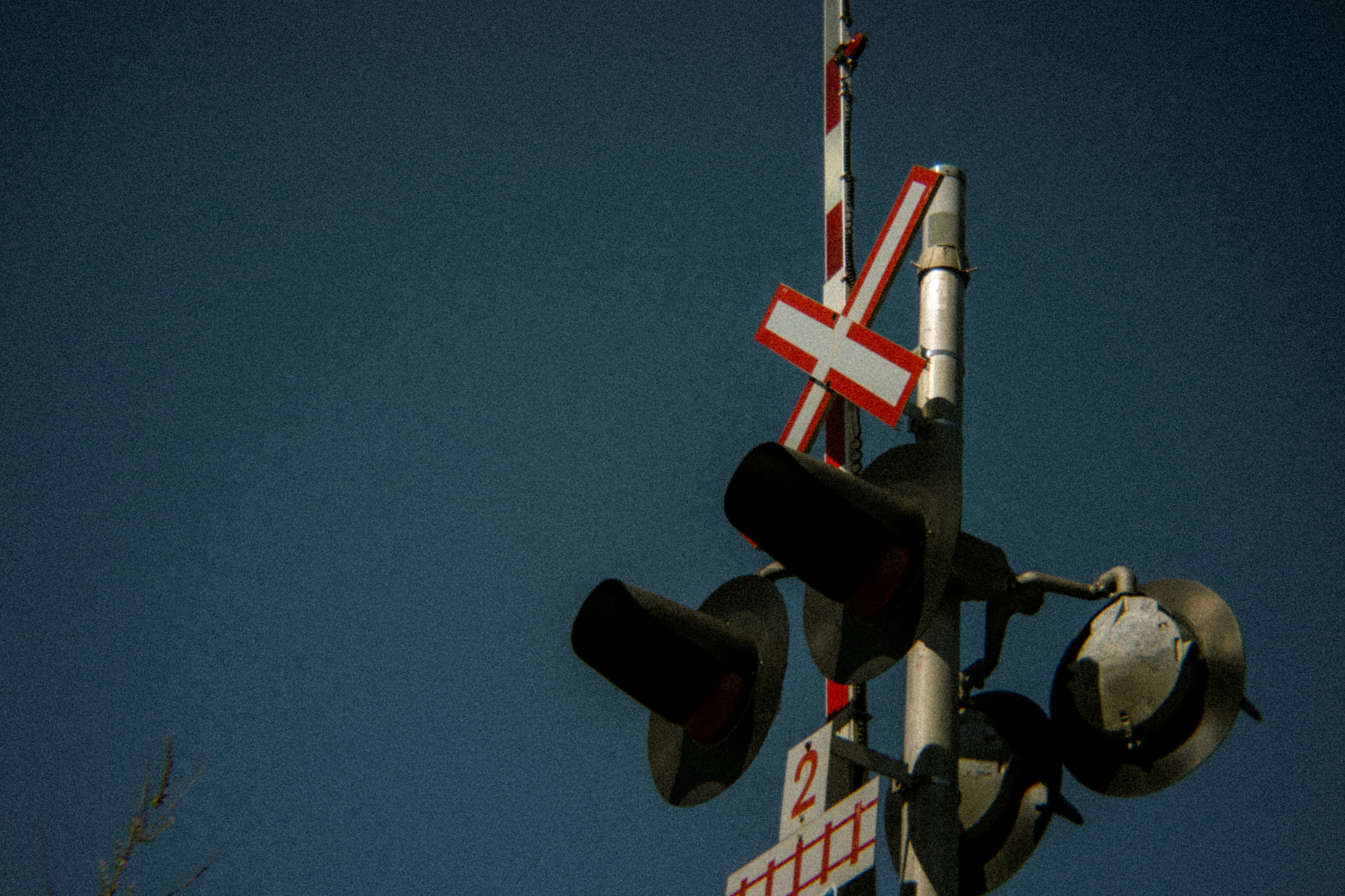 Railroad crossing signal with a clear blue sky.