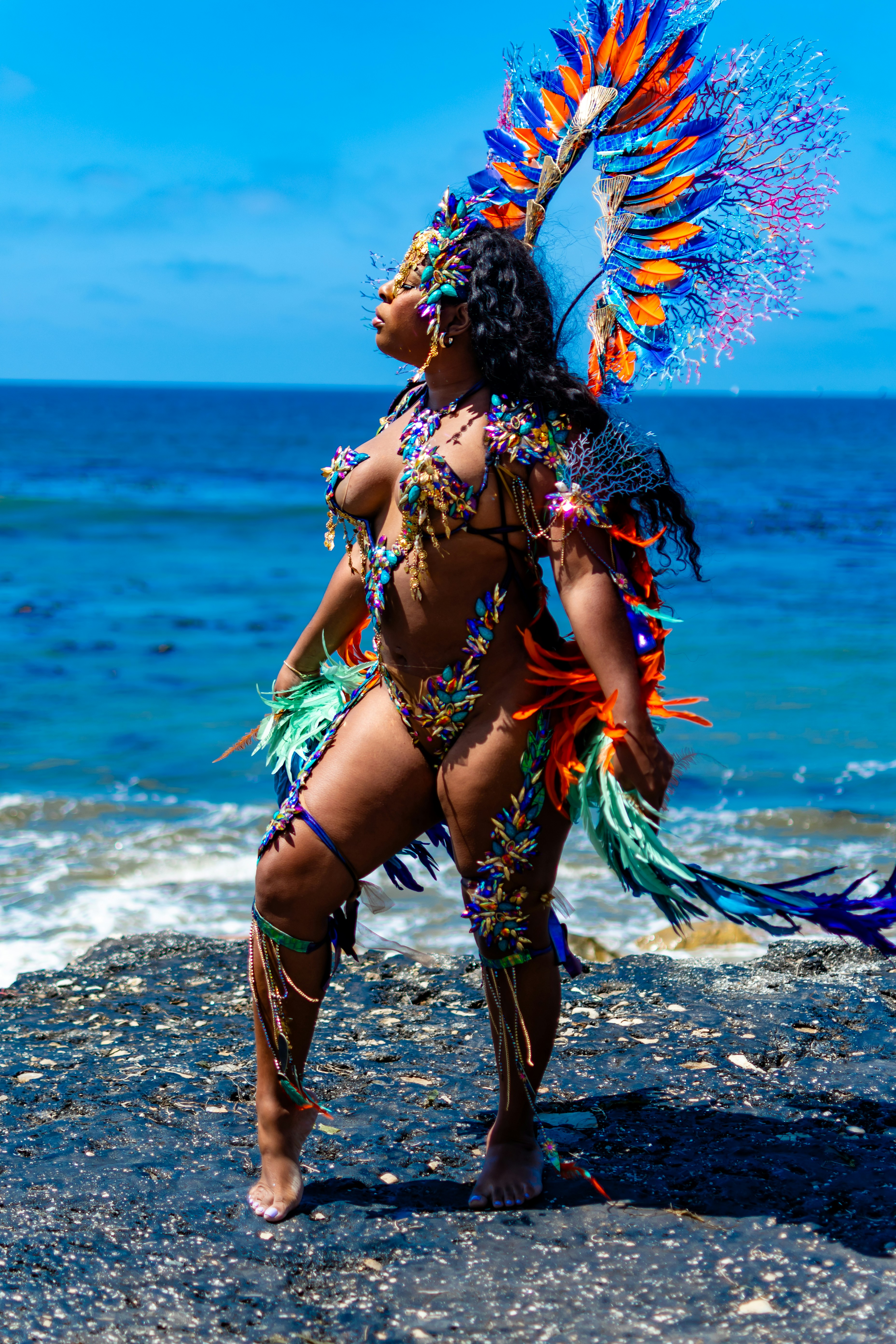 Woman in colorful carnival costume by the ocean.