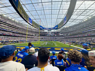 Spectators watch a football game in a modern stadium.