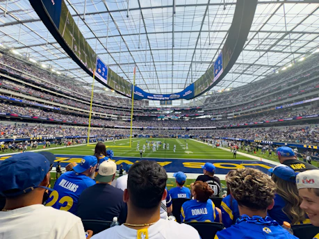 Spectators watch a football game in a modern stadium.