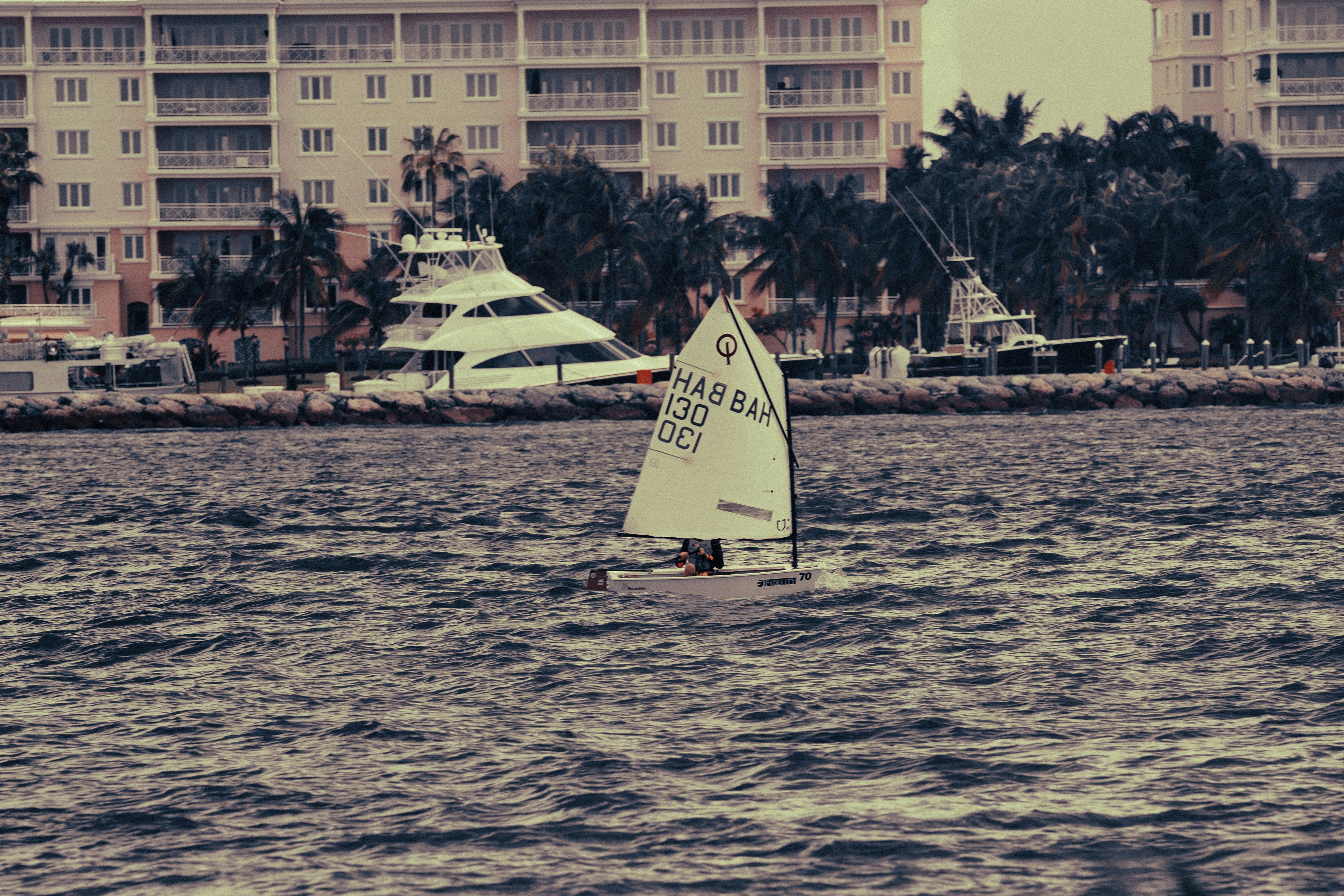 Small sailboat on choppy water with buildings behind