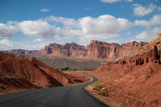 Winding road through a desert landscape with red rock formations.