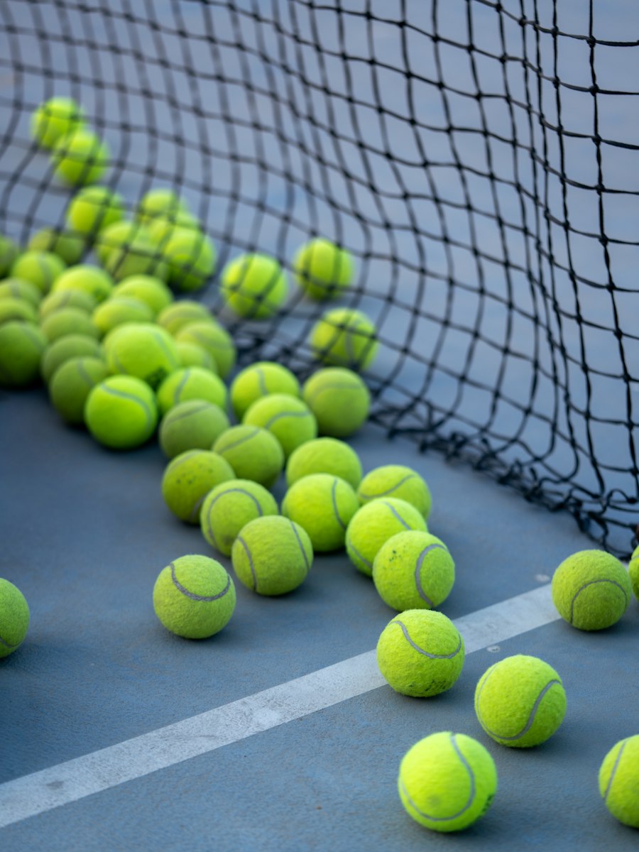 Nhiều quả bóng tennis trên mặt sân gần lưới - sơn sân thể thao