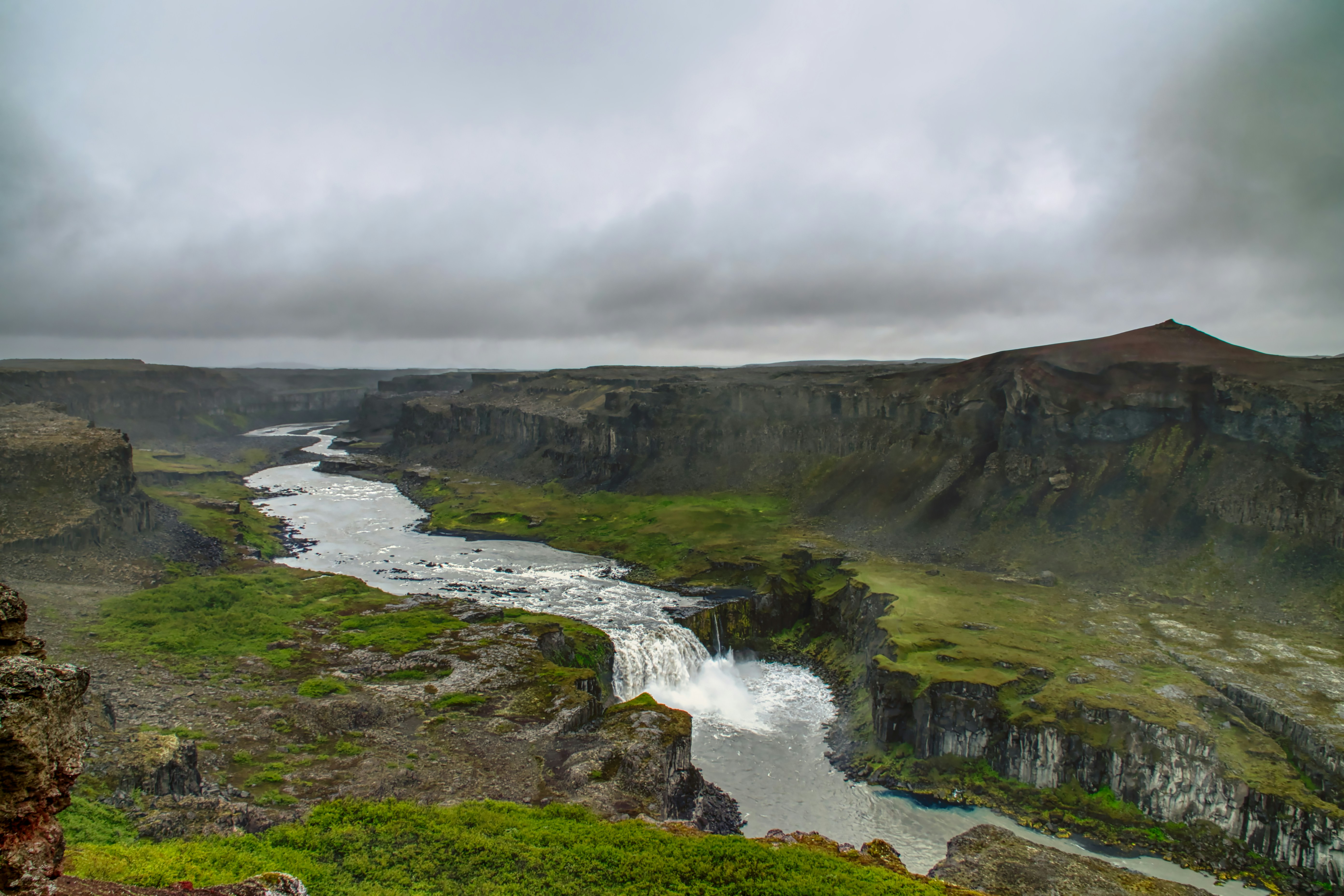 River flowing through a lush green canyon under cloudy skies
