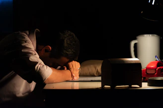 Man resting head on desk in dark room