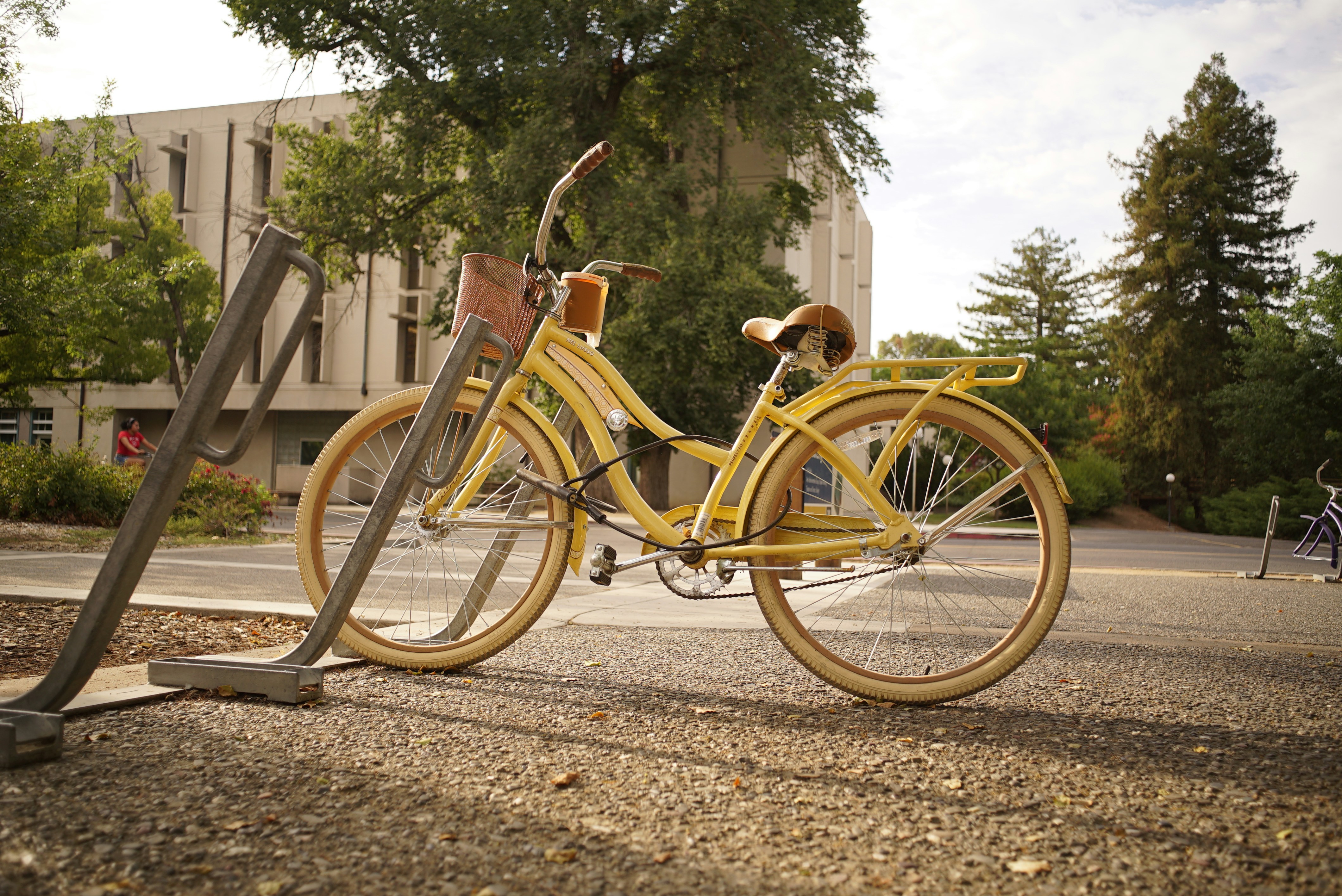 A yellow bicycle parked at a rack.