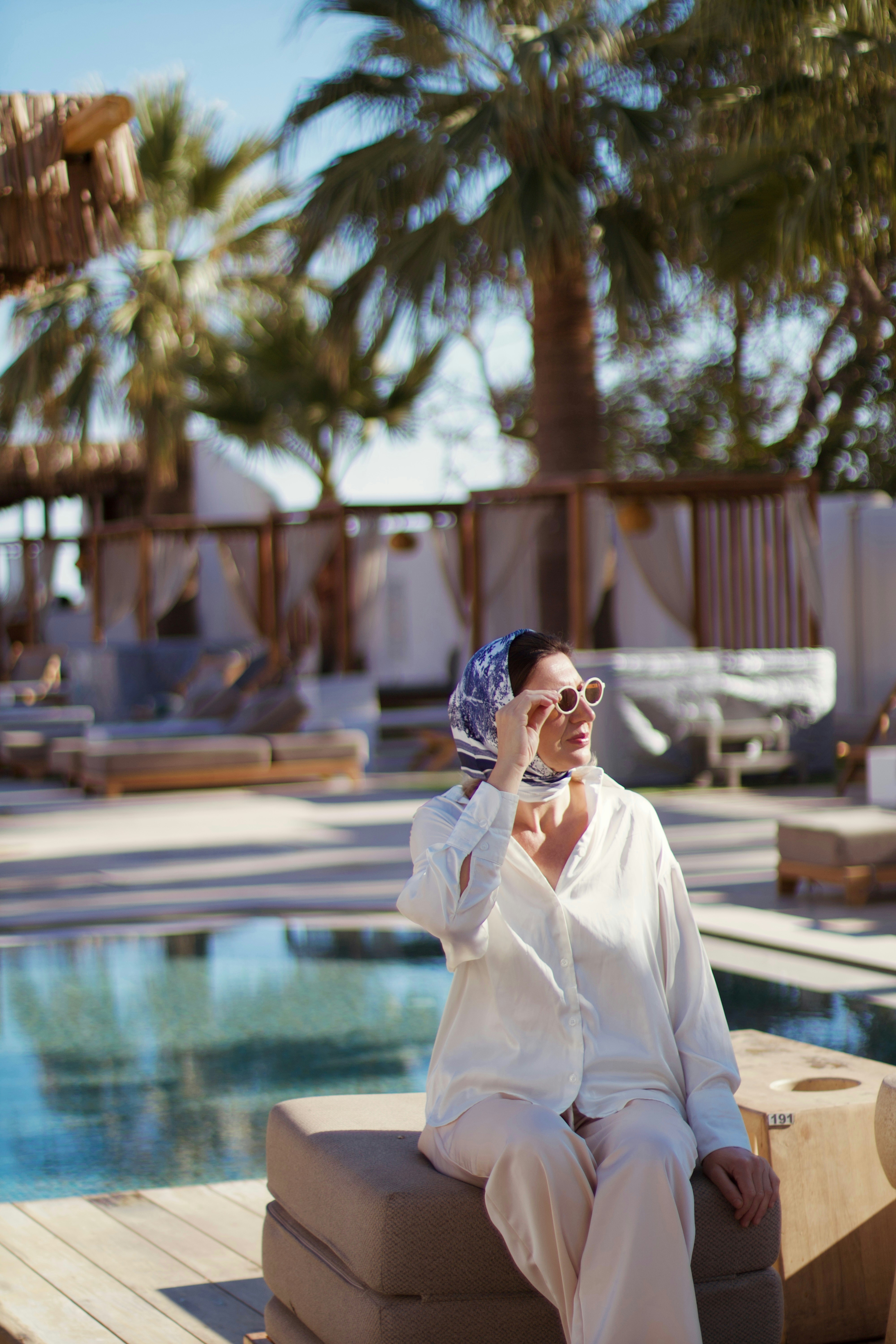 Woman in sunglasses relaxes by a resort pool