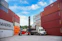 Forklift moving shipping containers at a port.