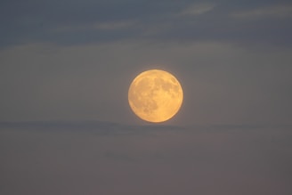 Full moon glowing through hazy clouds at dusk
