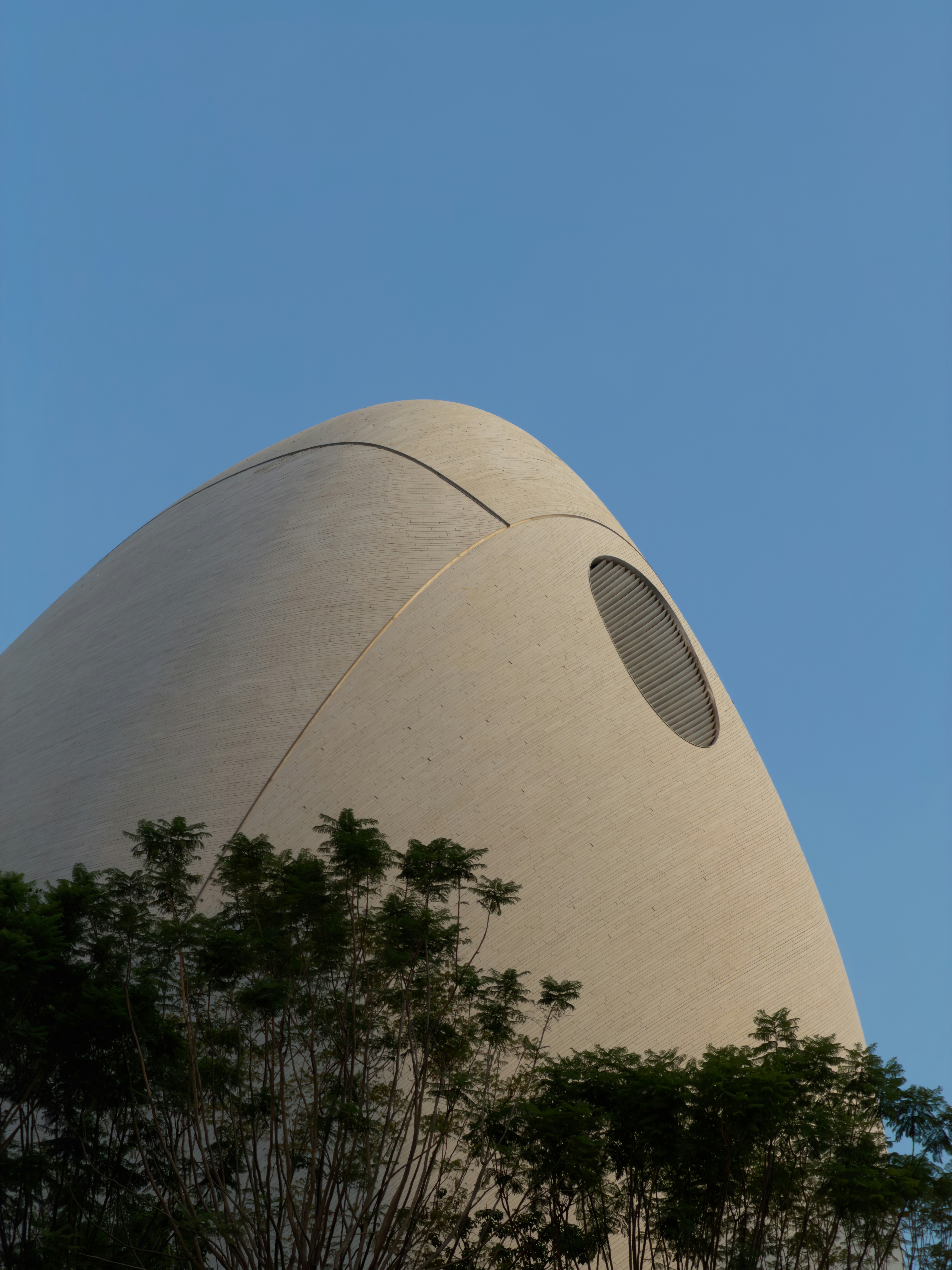 Modern building with rounded facade and circular window.