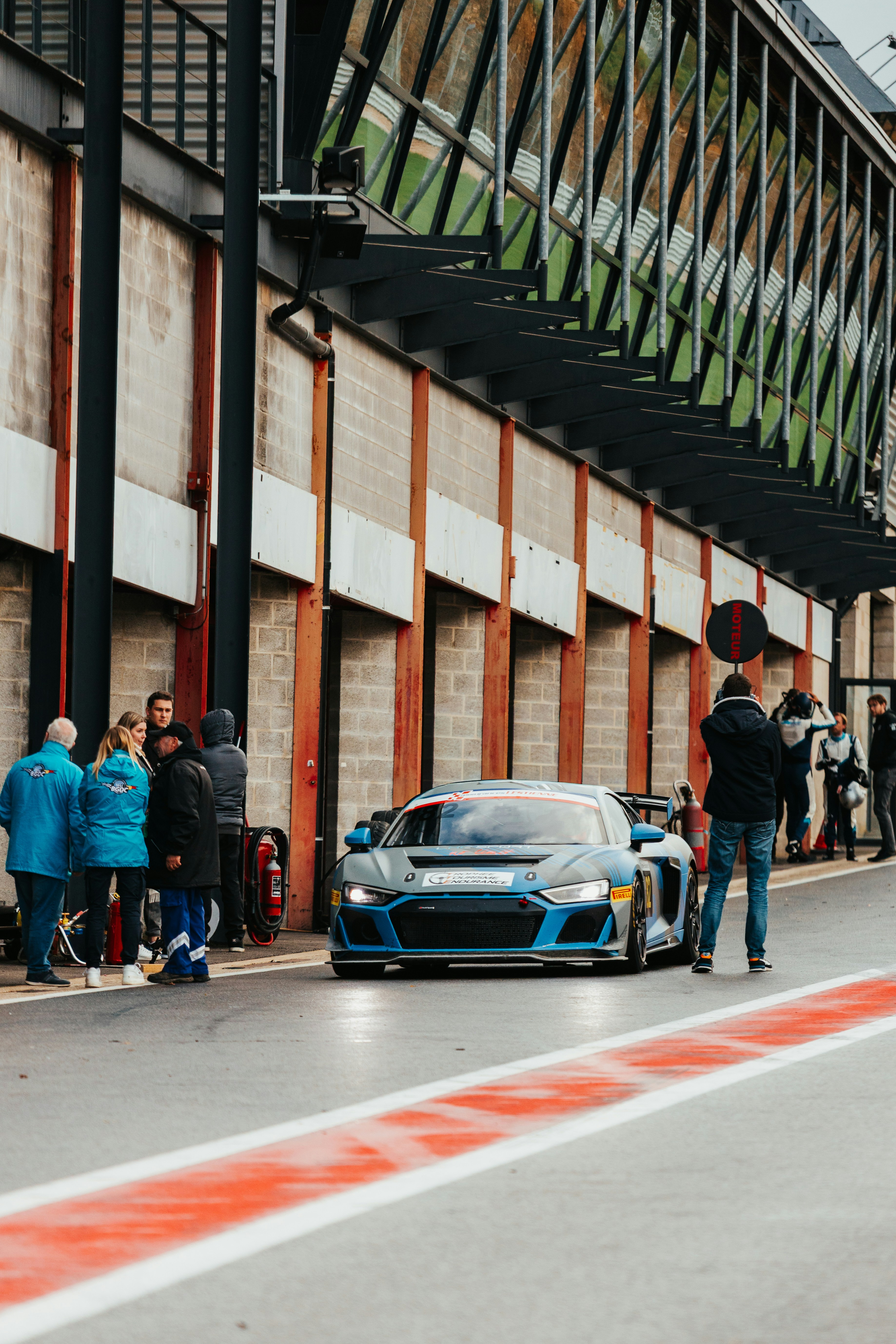 Rennwagen fährt unter Beobachtung der Crew in die Boxengasse ein