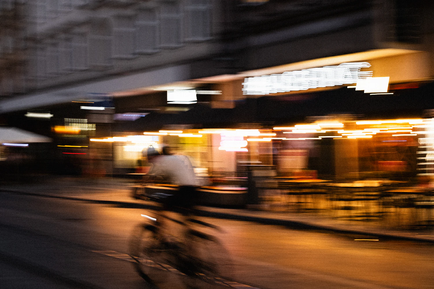 A cyclist smears across the frame at 1/30 s but freezes at 1/500 s, the same trade the table shows when depth of field is bought with a slower shutter.