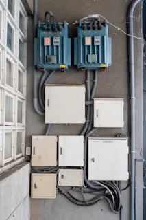 Electrical boxes and transformers mounted on a wall.