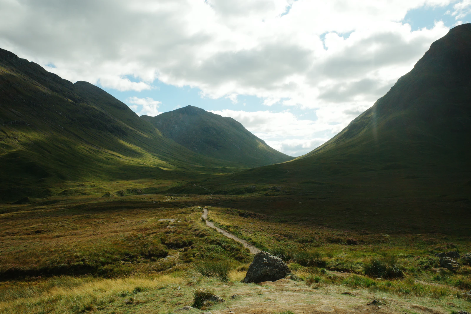 Winding path through a lush green mountain valley in the Scottish Highlands