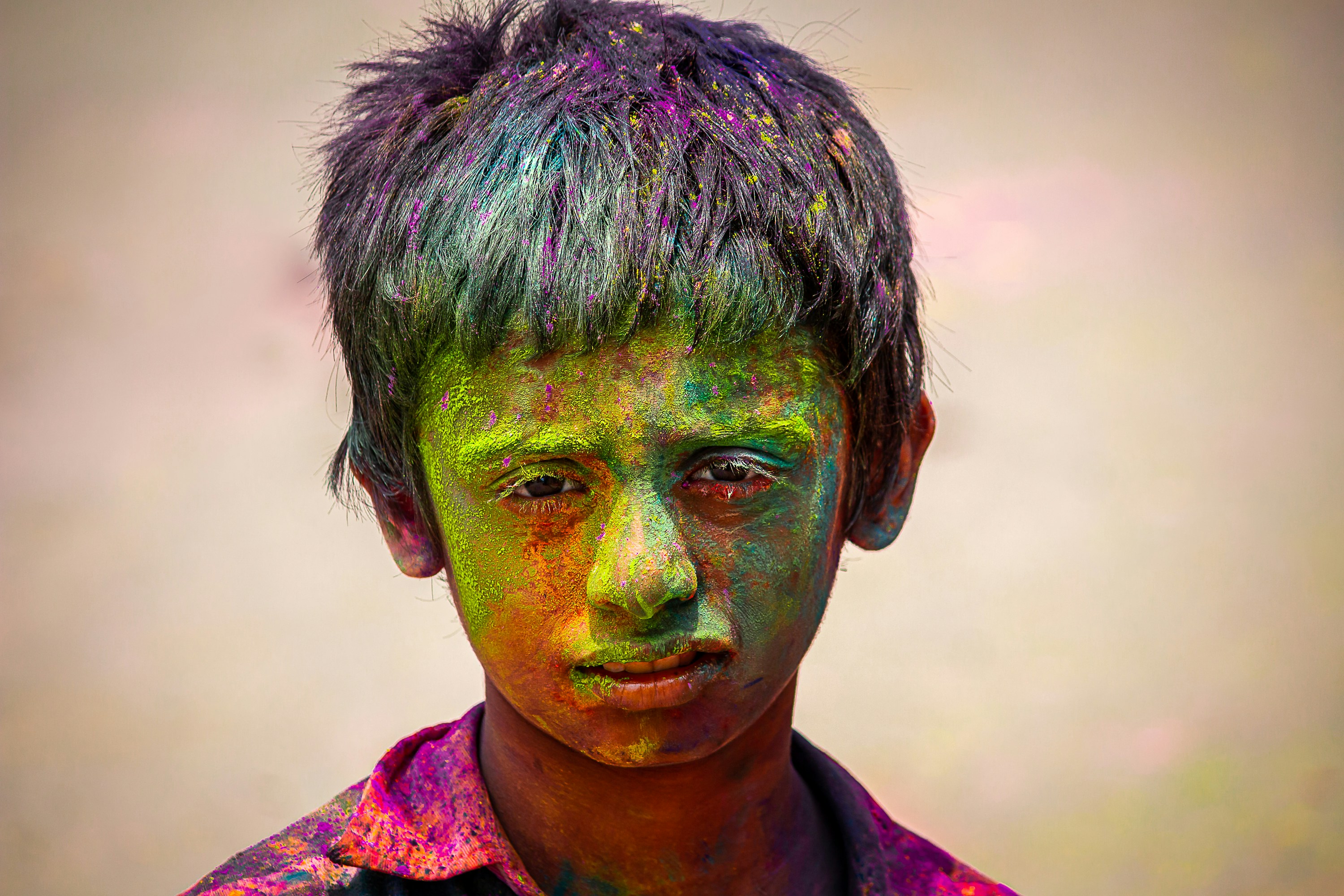 Young boy with colorful powder on his face.
