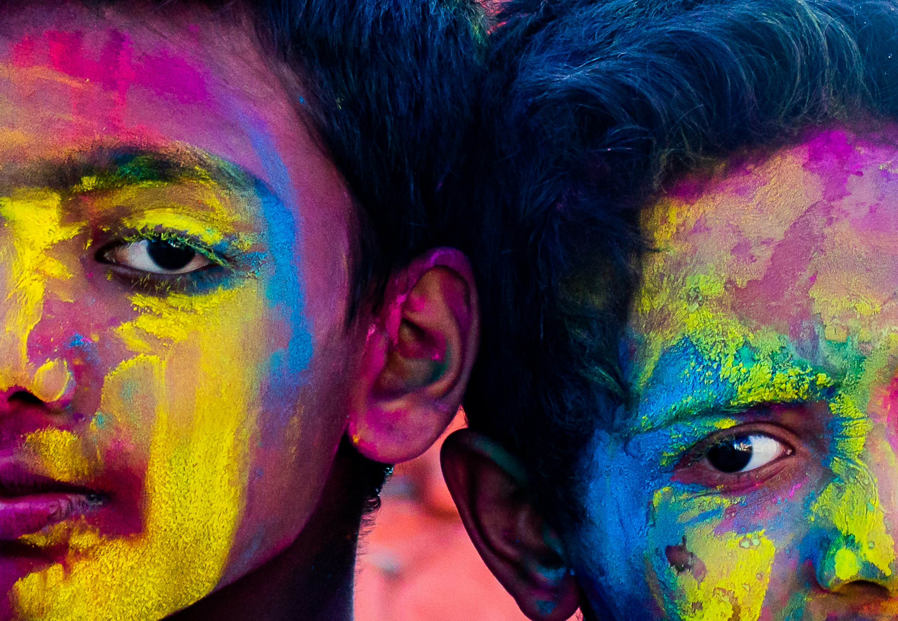 Two faces covered in vibrant holi powder