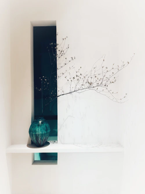 Dark vase and branches in a minimalist niche