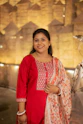 A woman in a red kurta smiles brightly.
