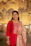 A woman in a red kurta smiles brightly.
