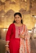 A woman in a red kurta with a floral scarf.