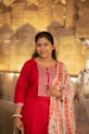 A woman in a red kurta with a floral scarf.