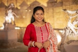 A smiling woman in a red outfit stands outdoors.