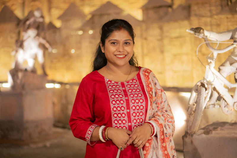 A smiling woman in a red outfit stands outdoors.