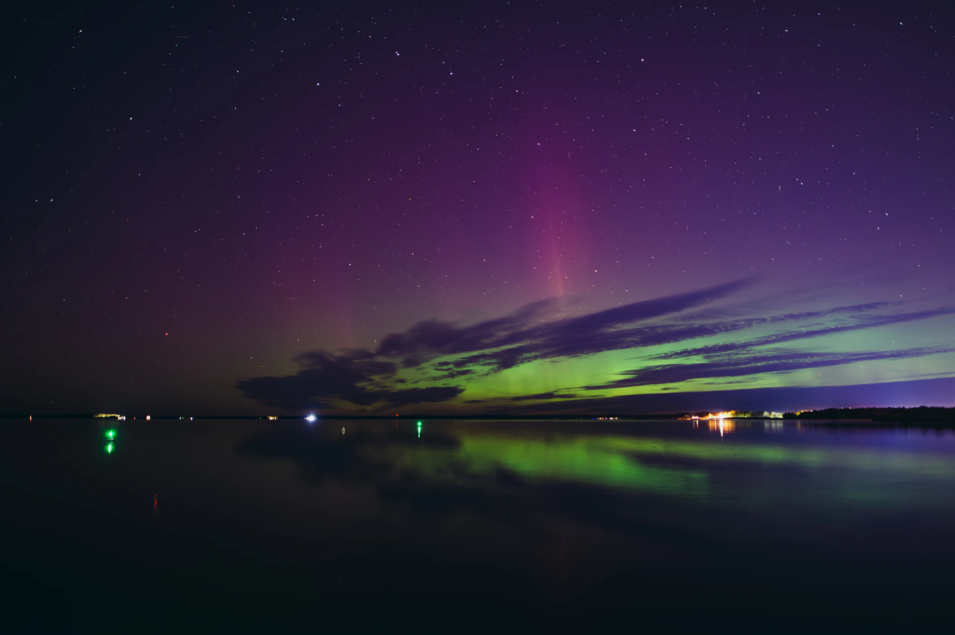 Aurora borealis over a calm lake at night.