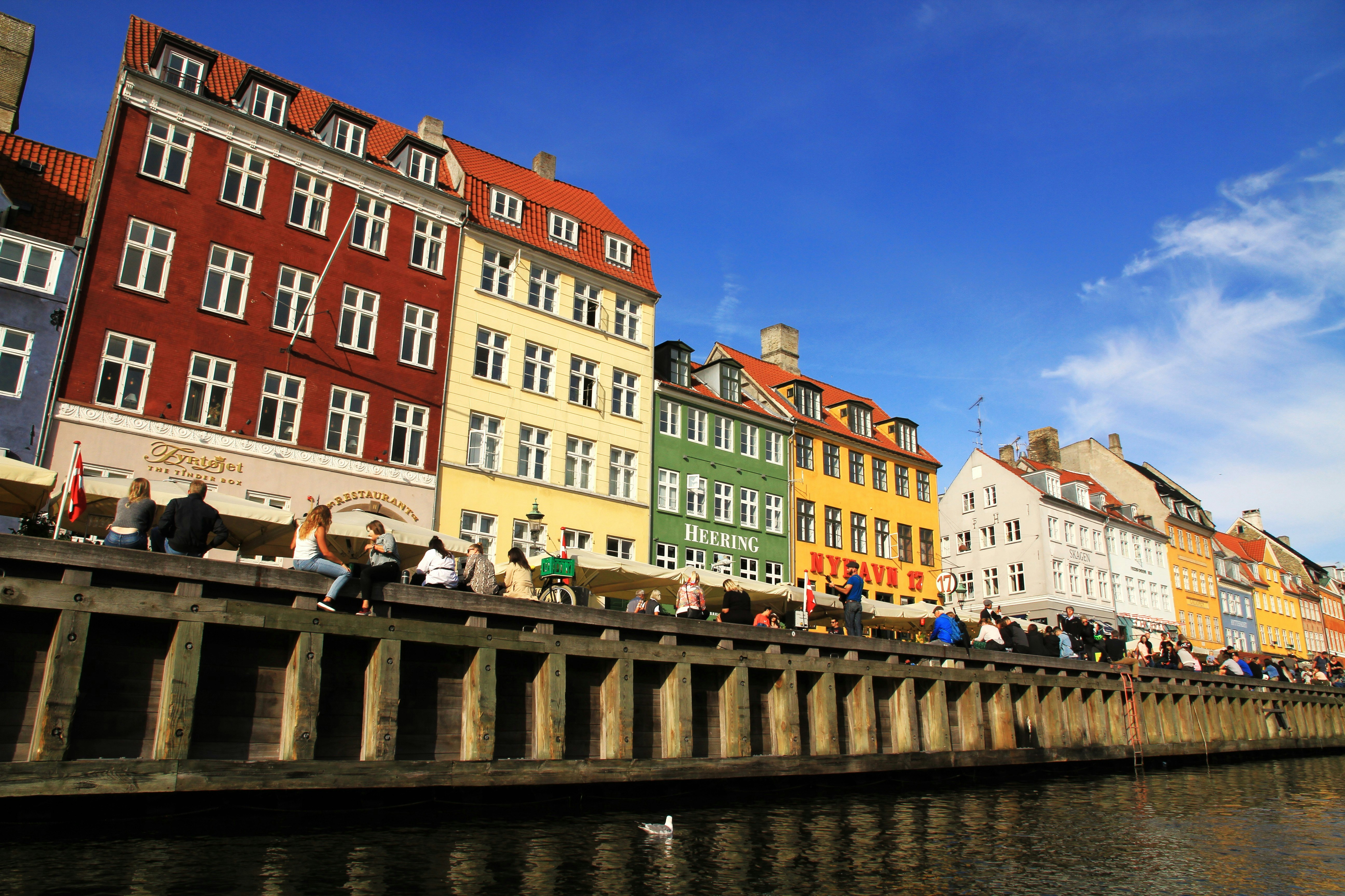 Edifici colorati fiancheggiano un canale con persone che si rilassano.